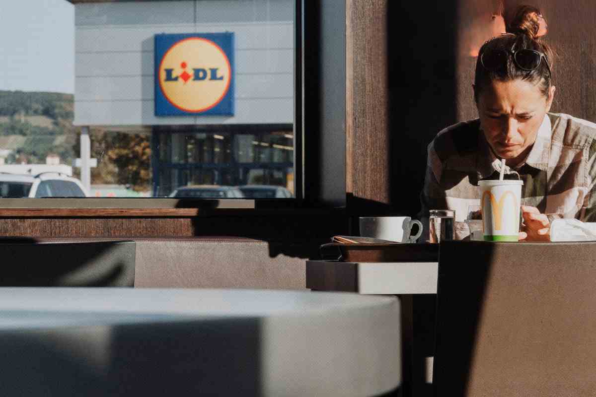 ragazza in un bar davanti a un punto vendita lidl