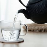 teiera che versa bicchiere di acqua calda