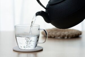 teiera che versa bicchiere di acqua calda