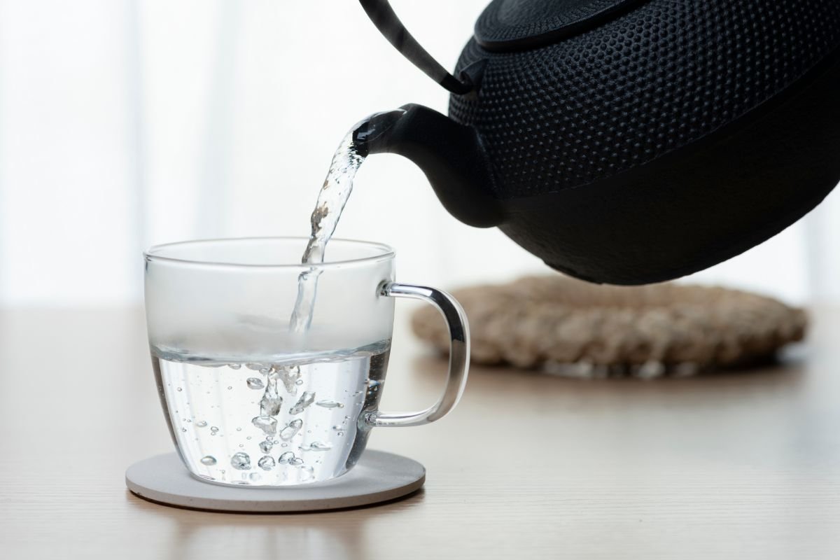teiera che versa bicchiere di acqua calda