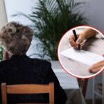 donna vedova seduta di spalle ad un tavolo e in primo piano una persona che firma un assegno