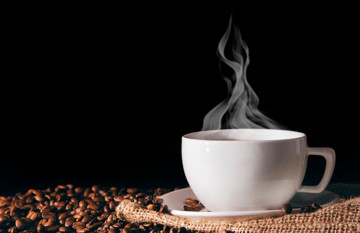 tazza di caffè fumante con chicchi