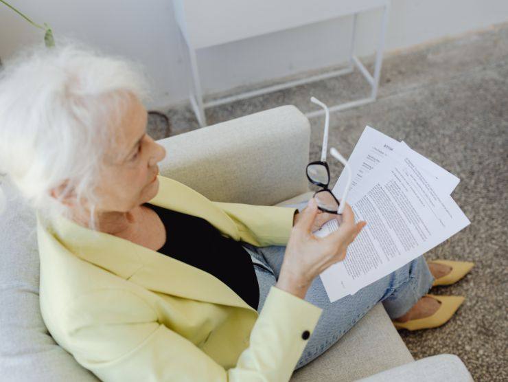 donna matura seduta sul divano che legge delle carte