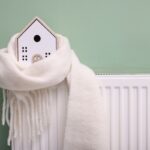 modellino di casa avvolto in una sciarpa poggiato su un termosifone