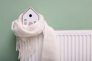 modellino di casa avvolto in una sciarpa poggiato su un termosifone