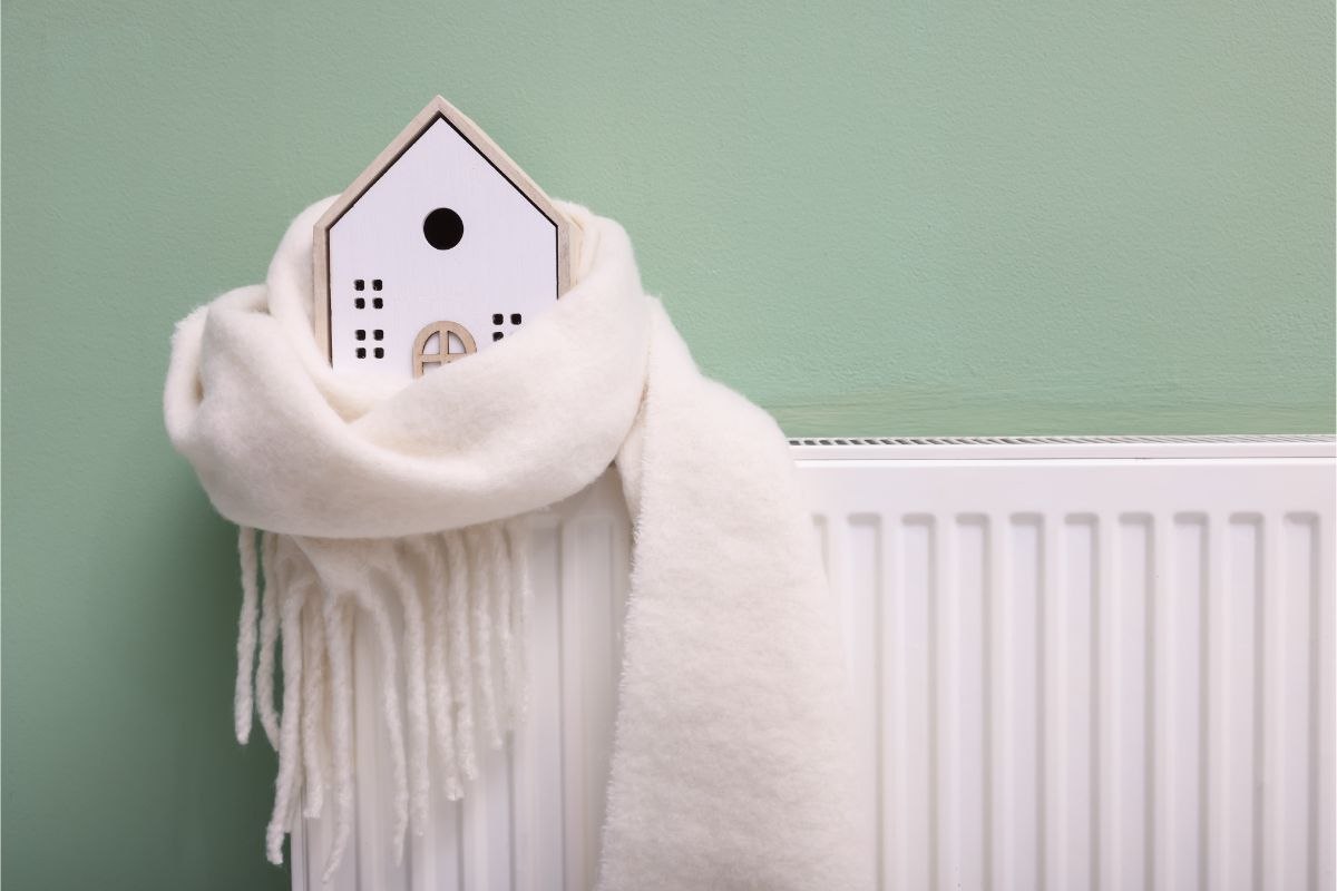 modellino di casa avvolto in una sciarpa poggiato su un termosifone